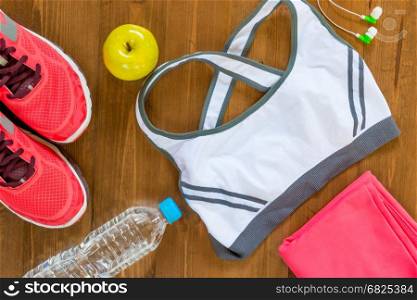 on a dark wooden floor sports objects and women's clothing top view