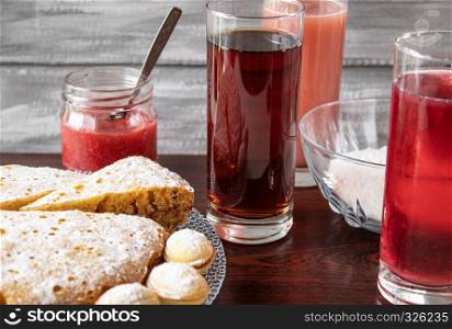 On a dark wooden table, juice in a glass in the background, a pie on a bowl and jam in a small jar.. Juice in a glass in the background, a pie on a bowl and jam in a small jar.