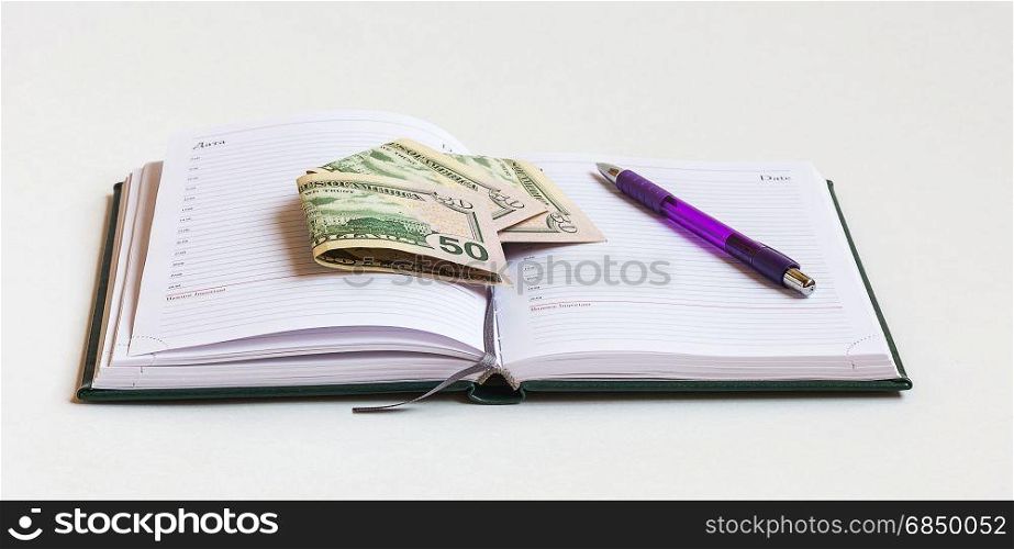 On a light background is open daily in the pages of which are bank notes and pen
