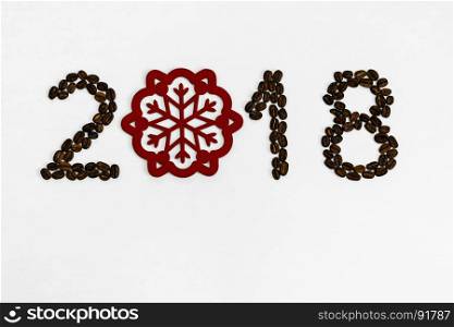 On a light background of coffee beans numbered 2018 with a red snowflake