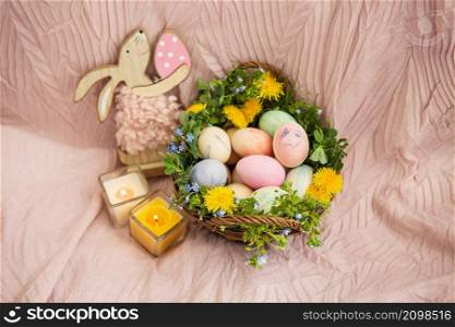 On a pastel bedspread is a basket of grass and various bright flowers, a rabbit. The basket contains Easter eggs painted with watercolors in beautiful pastel colors. On a pastel bedspread is a basket of grass and various bright flowers, a rabbit. The basket contains Easter eggs painted with watercolors in beautiful pastel colors.