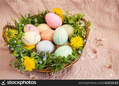 On a pastel cover a basket with herbs and bright flowers. The basket contains Easter eggs painted in watercolor in beautiful pastel colors. Great Easter. On a pastel cover a basket with herbs and bright flowers. The basket contains Easter eggs painted in watercolor in beautiful pastel colors. Great Easter.