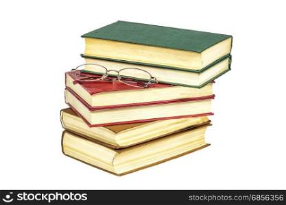 On a pile of hard-bound books lie reading glasses