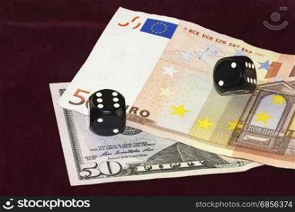 On a red cloth of visible part of the fifty dollar bills and fifty euros. On the bills are black cubes for poker