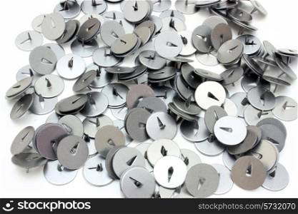 On a table there is a heap of buttons for a paper. They metal and sharp.