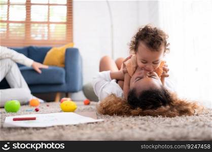On a vacation morning, parents and children are having fun playing in the living room, with the father hoisting his daughter up behind her mother.