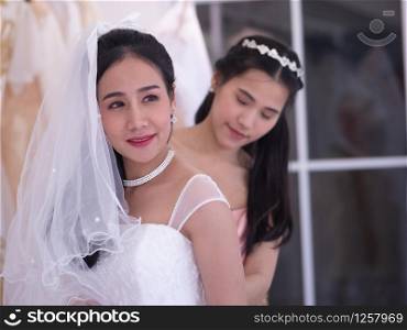 On a wedding day, bridesmaid helping the bride to preparation the bride gown in the dressing room before the marries ceremony.