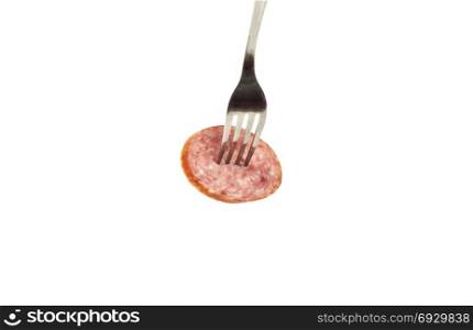 On a white background a piece of sausage is pinned on a metal fork
