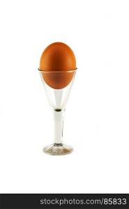 On a white background is a glass on a high leg with a chicken egg