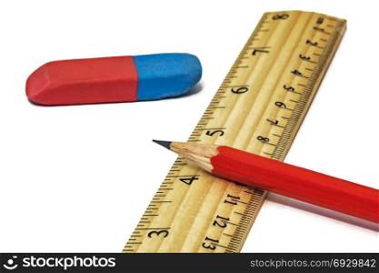 On a white background lie an eraser with a ruler and a simple pencil close-up