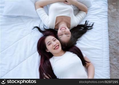On a white bed, an LGBT couple is gently kissing each other&rsquo;s foreheads.