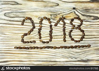On a wooden background, coffee beans numbered 2018 with an underscore