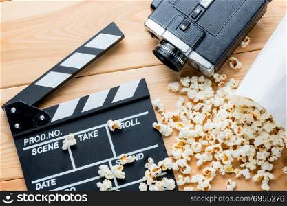 on a wooden background outdoor video clapper, retro video camera and salted popcorn