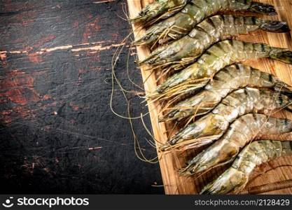 On a wooden cutting board raw shrimp. Against a dark background. High quality photo. On a wooden cutting board raw shrimp.