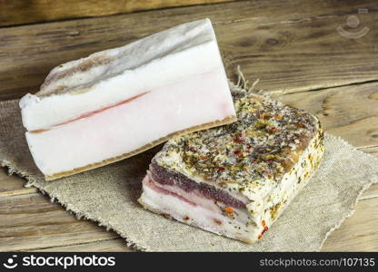 On a wooden surface on a napkin lies a rustic salted bacon