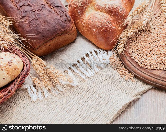 On a wooden table covered with burlap and linen napkins. On a napkin placed rye and wheat bread. Wooden cutting board and basket of bread on a sacking. Ears and grain on a wooden cutting board. Baking lying in a wicker basket.. Rye spikelets, wheat bread, bun in the basket. Canvas, burlap, wooden table, wooden cutting board.