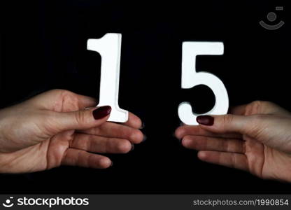 On black background female hands with number fifteen.. On the female palms figure fifteen.