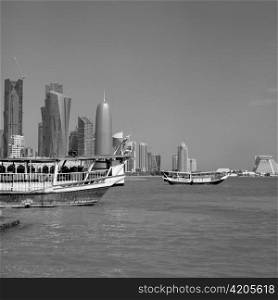 On dhow sails on a sightseeing trip around Doha Bay, Qatar, while another waits for passengers. Medium format film photo.