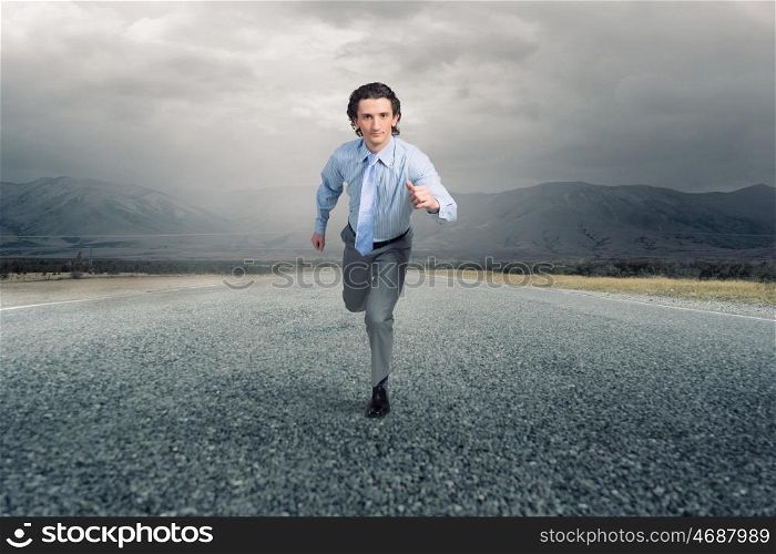 On his way to success. Young businessman in suit running outdoor on asphalt road