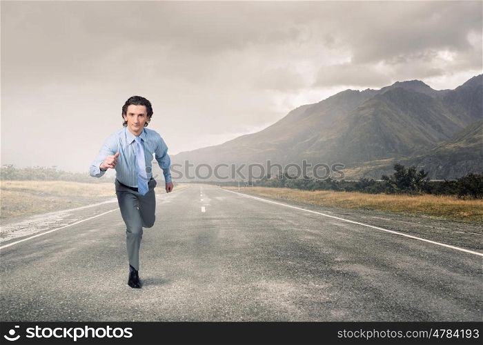 On his way to success. Young businessman in suit running outdoor on asphalt road