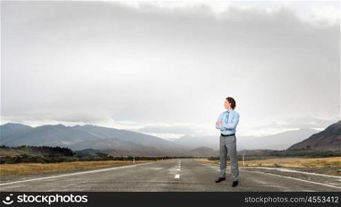 On his way to success. Young confident businessman with arms on chest on asphalt road