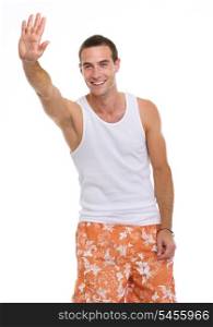 On holiday smiling young man in shorts and t-shirt saluting
