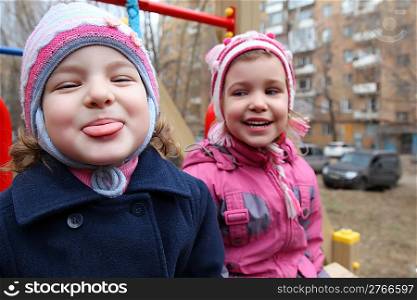 On playground the girl puts out tongue, second laughs