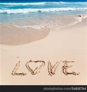 On sand at ocean edge it is written LOVE