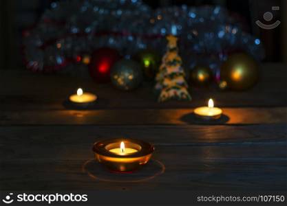 On the background of Christmas and New Year's decorations, a candle burns in a decorative stand