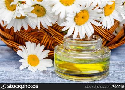 On the blue boards near the basket with chamomile flowers there is a bank of light chamomile essential oil.. On the boards near the basket with chamomile flowers there is a bank of light chamomile essential oil.
