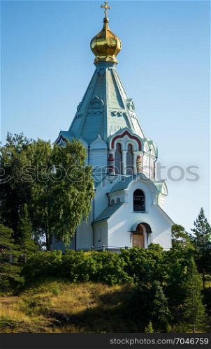On the hill there is a white and blue temple of the St. Nicholas monastery with a golden tent shining in the sun.