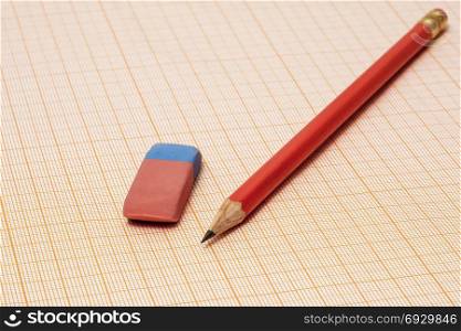 On the millimeter paper lie an eraser and a simple pencil close-up