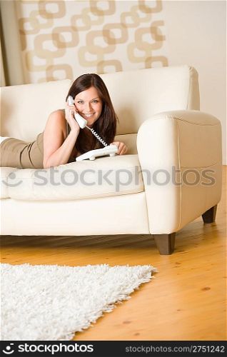 On the phone: young woman calling in lounge, lying down on sofa
