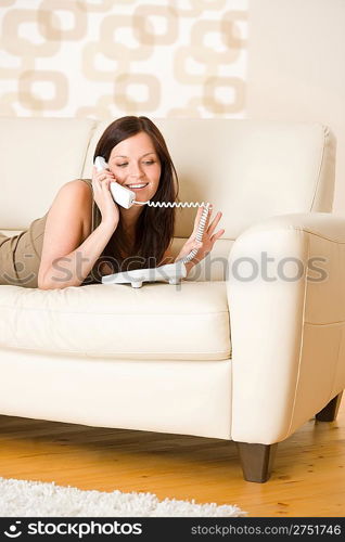 On the phone: young woman calling in lounge, lying down on sofa