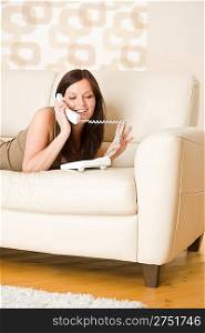 On the phone: young woman calling in lounge, lying down on sofa