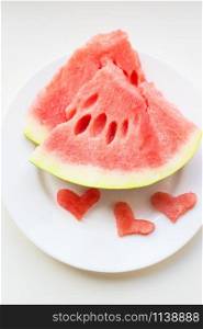 on the plate are two pieces of watermelon and a small heart-shaped. valentine card. watermelon on a white plate