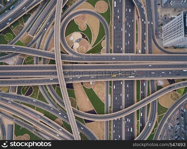 On the road going trucks, cars, trains. aerial view of road junction with railway tracks in Dubai, UAE