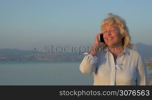On the sea coast city of Perea, Greece is walking a grown woman and talking on mobile phone