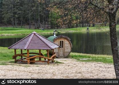 On the shore of the forest lake there is a bathhouse and a gazebo