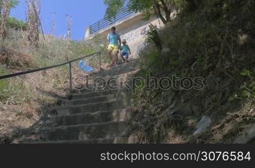 On the street of city Perea, Greece in park down the stairs father holding for hand of his son