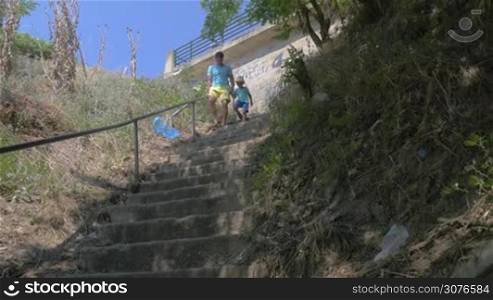 On the street of city Perea, Greece in park down the stairs father holding for hand of his son