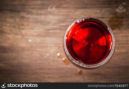 On the table red wine in a glass. Top view. On a wooden background.. On the table red wine in a glass. Top view.