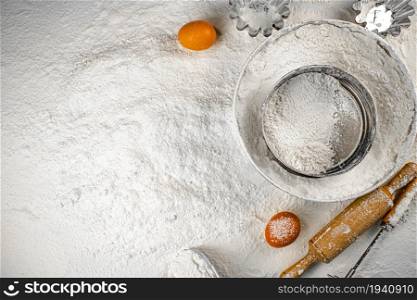 On the table sieve, rope and eggs in flour. Top view. On a white background. . On the table sieve, rope and eggs in flour. Top view.