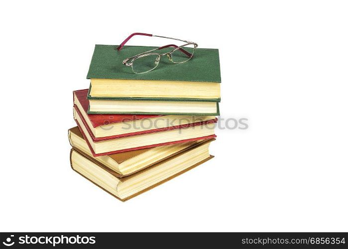 On the white surface is a pile of hard-bound books and reading glasses