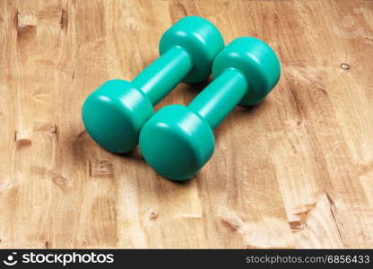 On the wooden surface are two dumbbells for sports