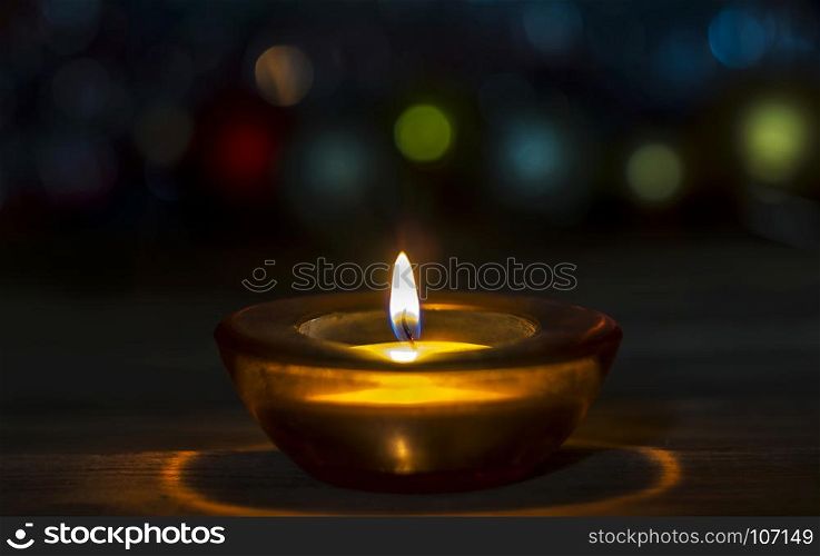 On the wooden surface is a decorative candle in a glass stand