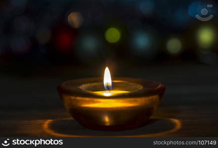 On the wooden surface is a decorative candle in a glass stand