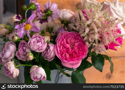 On the wooden surface laid out tools for flower bouquets: scissors, roses, colored ribbon, roses.. The workplace of the florist to work. Side view. Making floral decorations. Flowers on a old wooden table. Tools and accessories florists need for making up a bouquet.