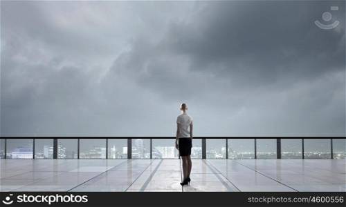 On top of business. Back view of businesswoman standing on roof looking at city