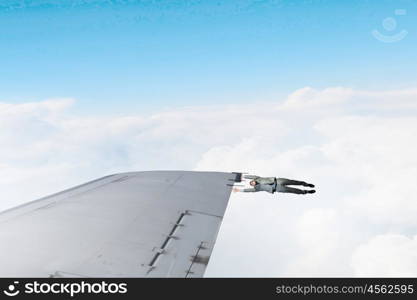 On wing of flying airplane. Young businessman flying on edge of airplane wing